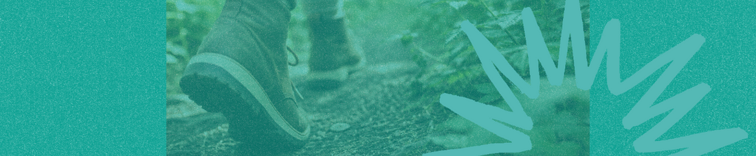Close-up of a person wearing brown boots taking a step on a lush green forest trail.