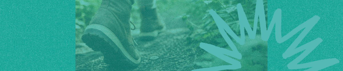 Close-up of a person wearing brown boots taking a step on a lush green forest trail.